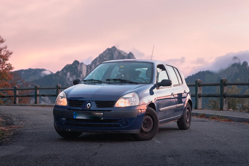 a small blue car parked on the side of a road