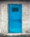 A bright blue metal door with a vent grid near the top, securely locked with a padlock. The door is set in a rough, textured gray concrete wall, suggesting an industrial or utilitarian setting.