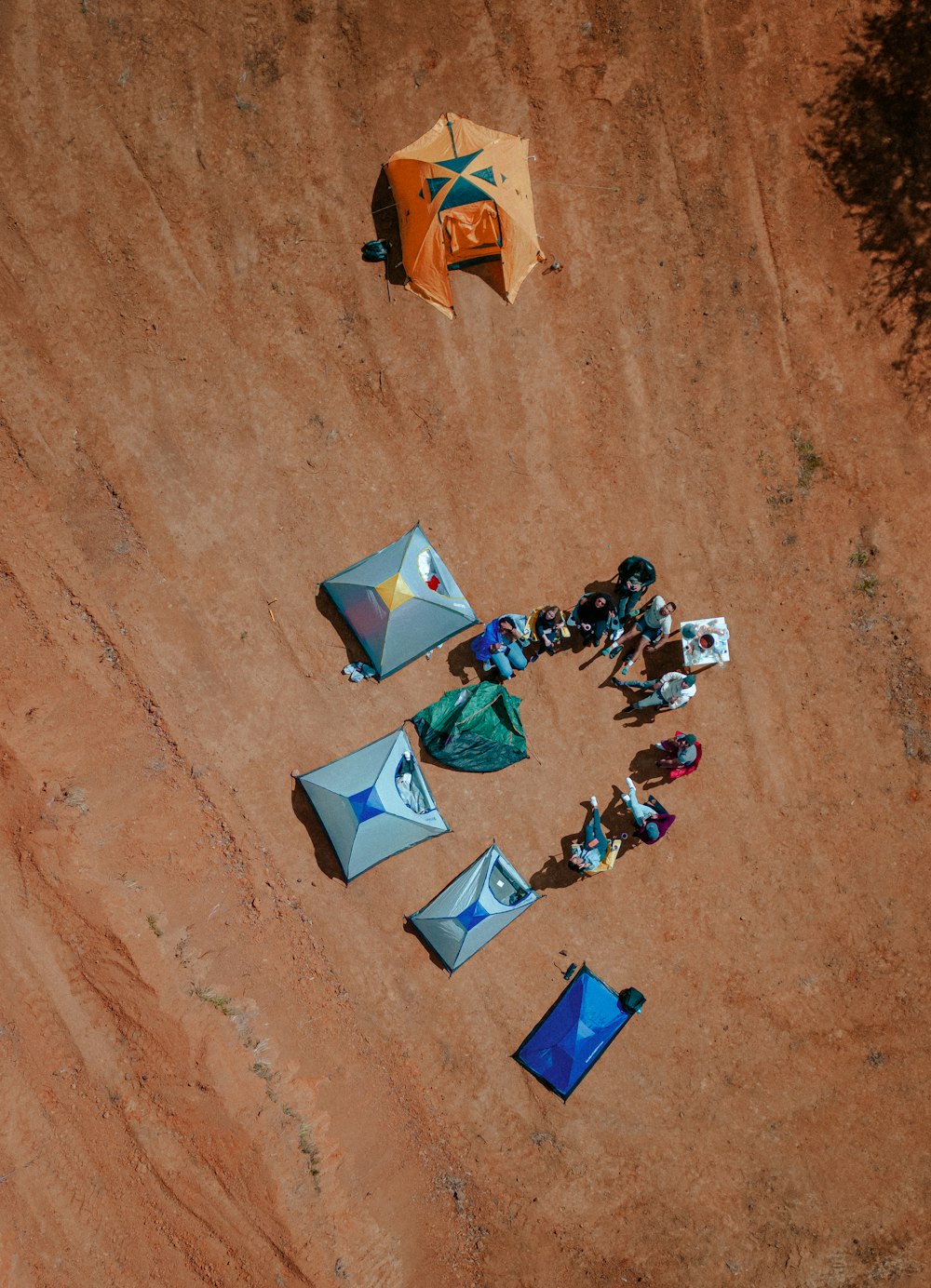 a group of people sitting on top of a dirt field