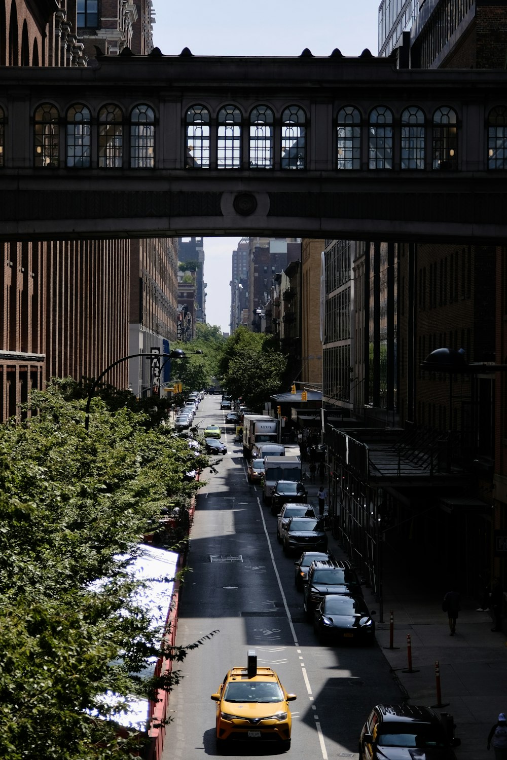 a yellow taxi cab driving down a street under a bridge