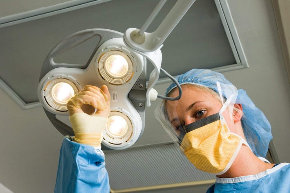 a woman in a surgical gown is operating a light fixture