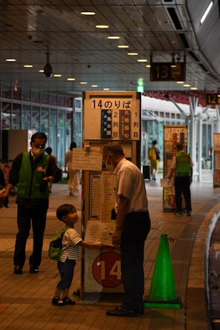 A dcc transit driver warmly greeting a parent and child at the bus stop during morning pickup.