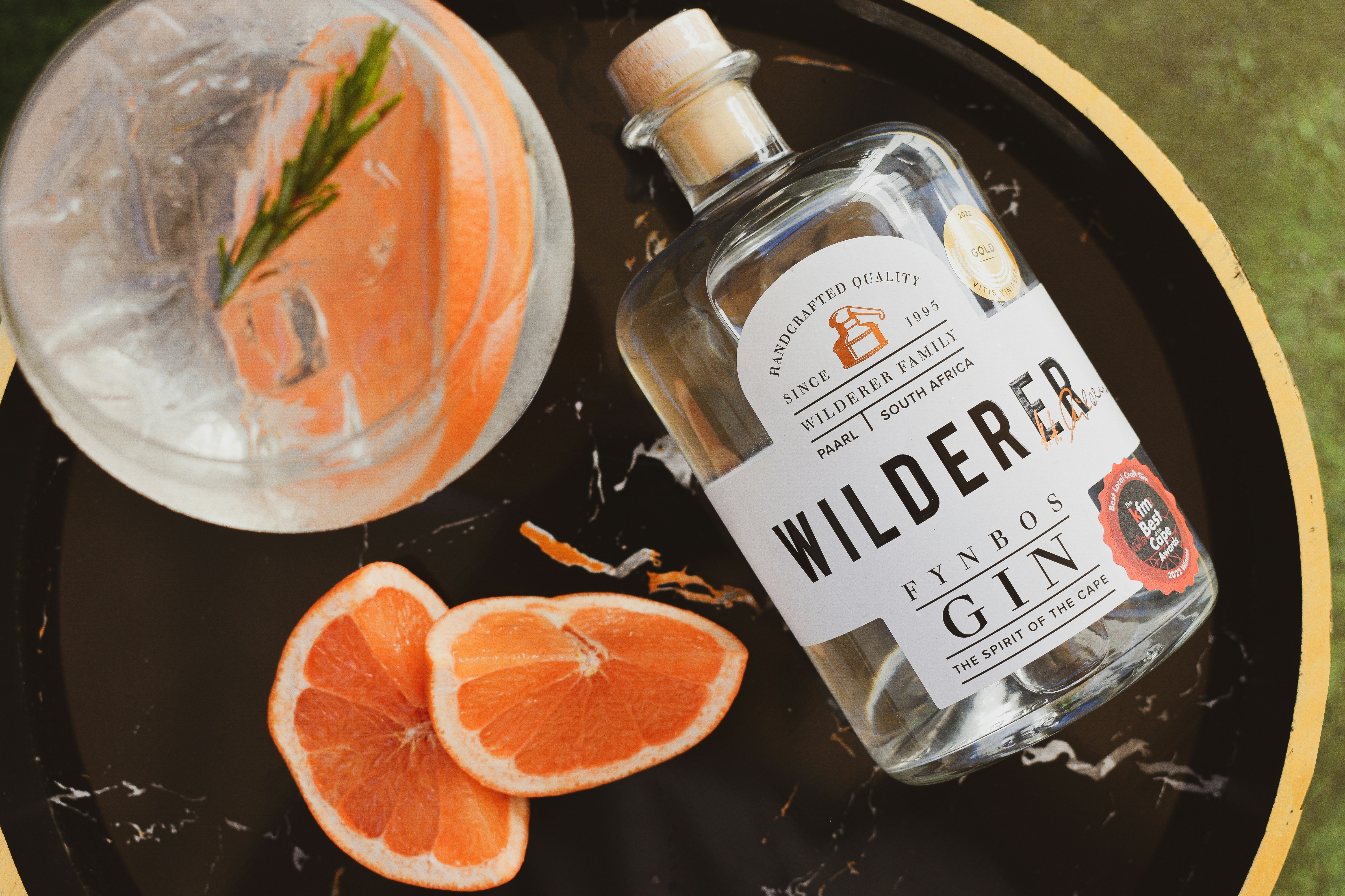 une bouteille de gin sauvage à côté d’oranges tranchées
