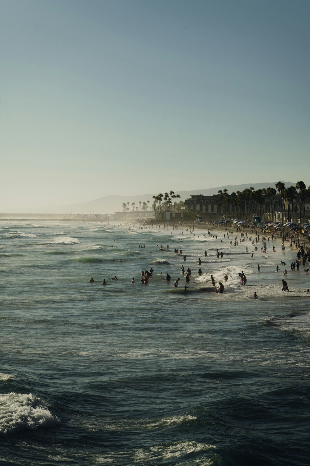 a crowded beach with people swimming in the ocean