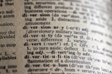 A close-up view of a dictionary page showing words and definitions related to 'diversion' and 'diversity'. The text is crisp with clear phonetic transcription and explanations in a serif font. The paper has a textured, off-white appearance, suggesting age or frequent use.