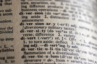 A close-up view of a dictionary page showing words and definitions related to 'diversion' and 'diversity'. The text is crisp with clear phonetic transcription and explanations in a serif font. The paper has a textured, off-white appearance, suggesting age or frequent use.