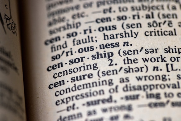 An open dictionary focusing on the word 'censorship' with related terms and pronunciations nearby. The print is clear, emphasizing the definitions and their phonetic transcriptions.