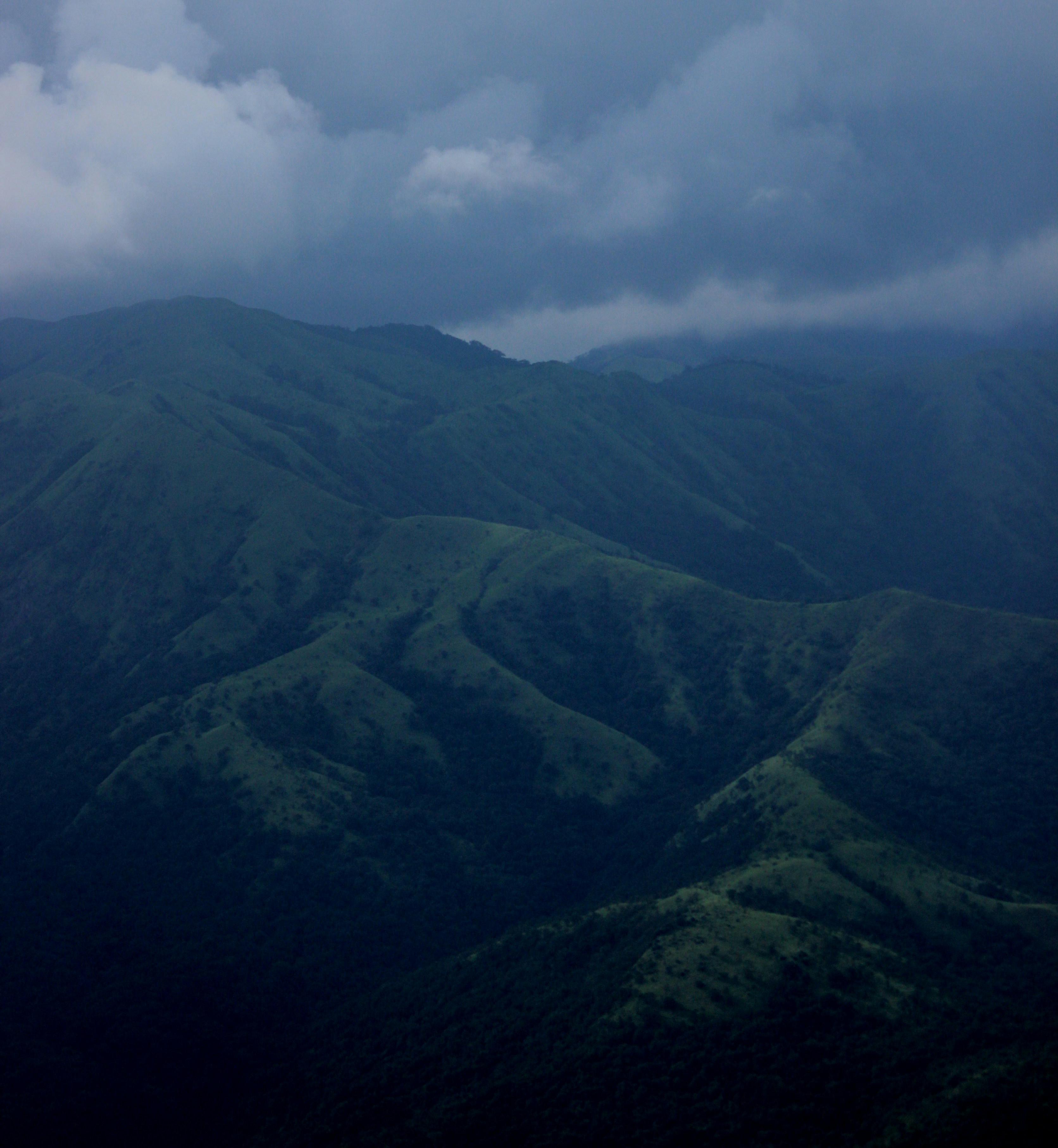 a plane flying over a lush green mountain range