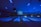 A dimly lit bowling alley with multiple lanes illuminated by blue lights. The ceiling features long light fixtures casting a faint glow. A large screen at the end of the lanes displays text. Walls are decorated with abstract patterns creating a futuristic or cosmic ambiance.
