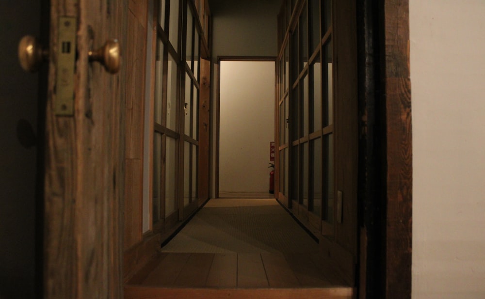 a narrow hallway with wooden doors leading to another room