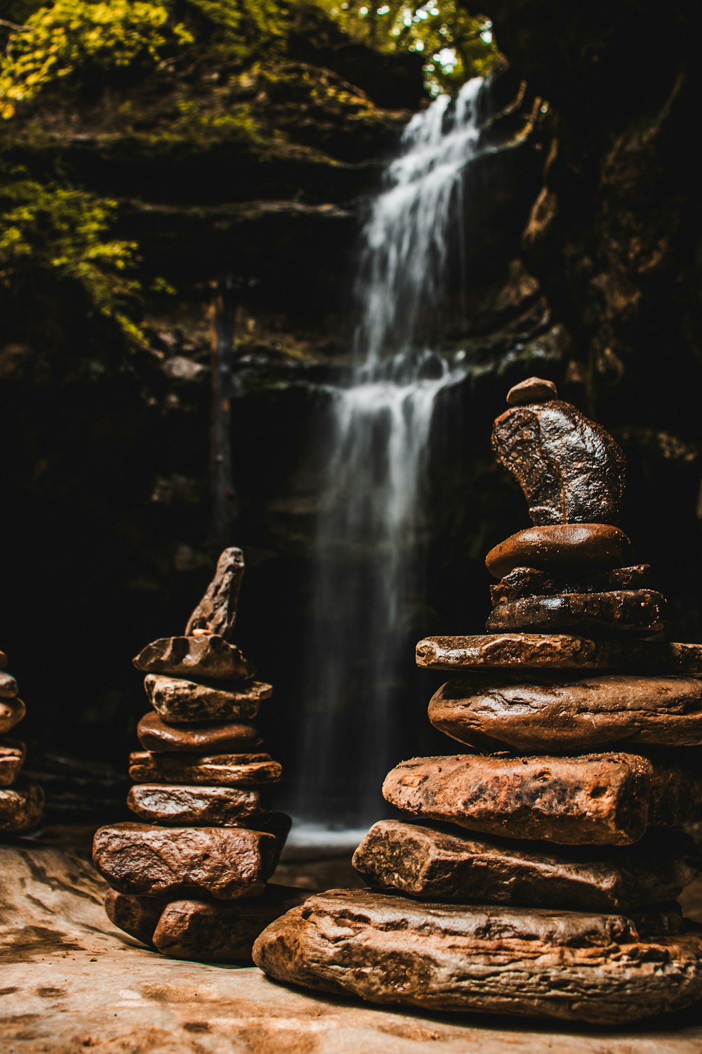 a pile of rocks sitting in front of a waterfall