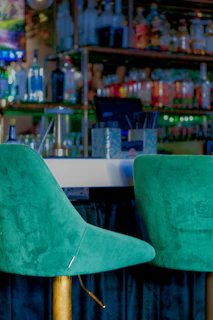 Elegant velvet barstool with gold metal legs and a tufted backrest, set in a chic home bar.