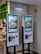 Two digital kiosks for placing takeout orders, displaying images of food items. They are located in a restaurant setting with visible payment interfaces and a sign above indicating 'Takeout Order' in both English and Chinese.