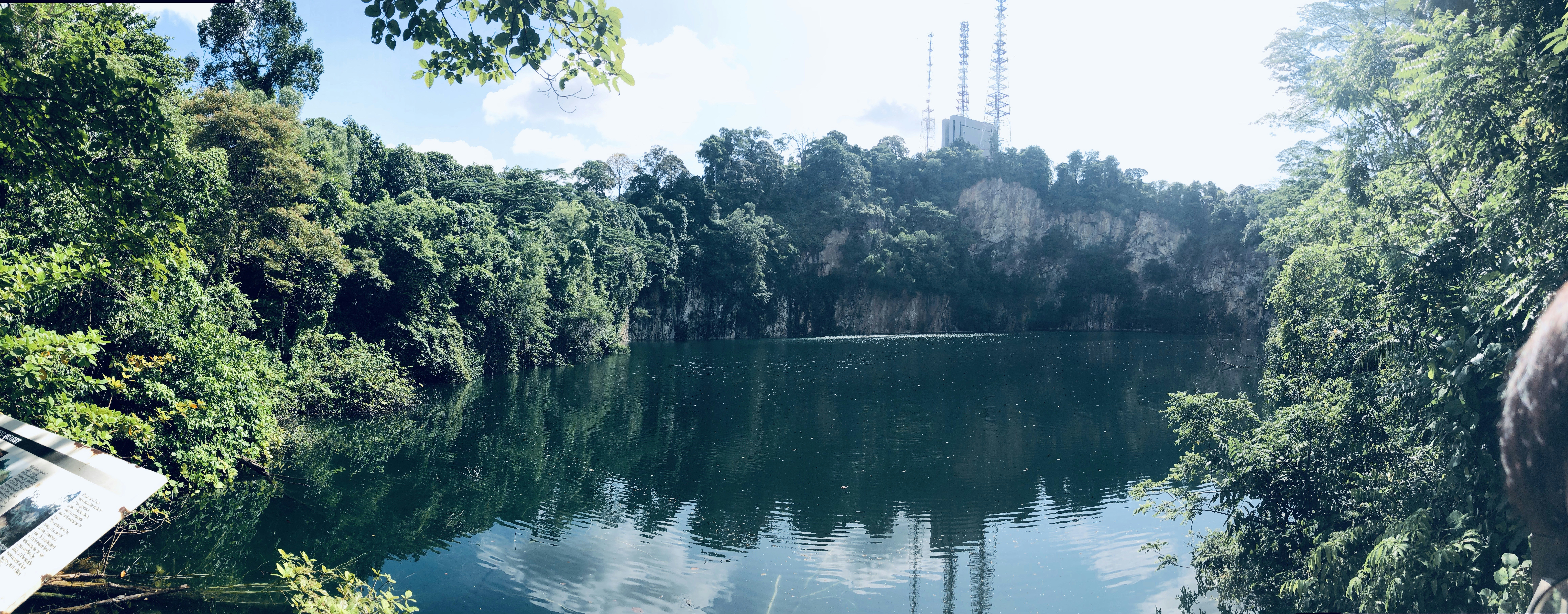 danau yang dikelilingi oleh pepohonan dengan menara radio di latar belakang