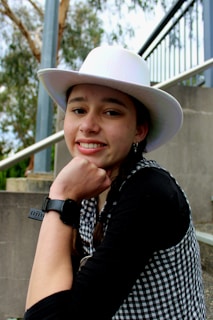 A happy customer wearing a custom-shaped cowboy hat outdoors on a sunny day.