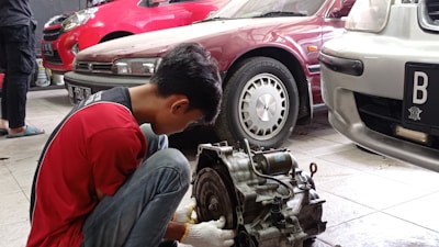 A mechanic installing a used car part on a vehicle in a garage.
