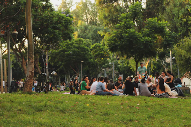 A diverse group of community members sharing stories and laughter in a sunlit park.