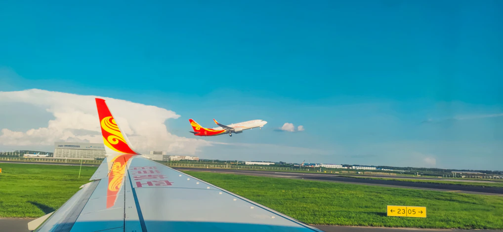 A vibrant airplane taking off against a clear blue sky, symbolizing national and international flights.