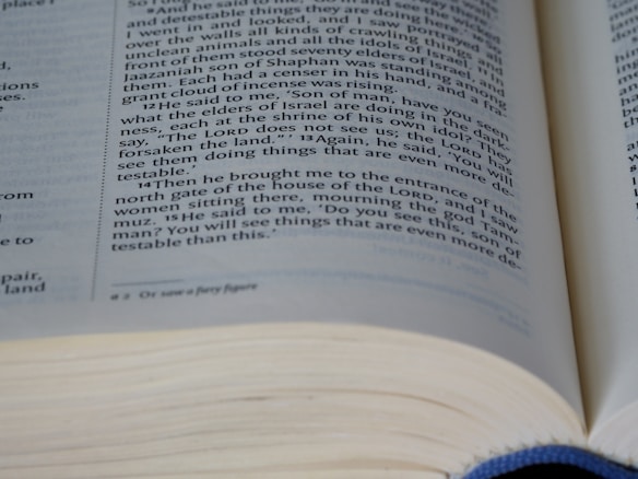 An open book with text written in English, with a focus on a specific page. The text appears to be part of a religious or spiritual scripture, containing paragraphs with chapter and verse numbers.