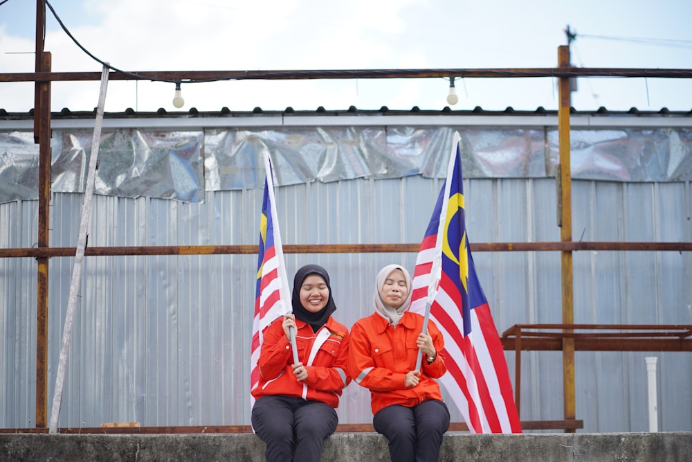 two women sitting next to each other holding flags