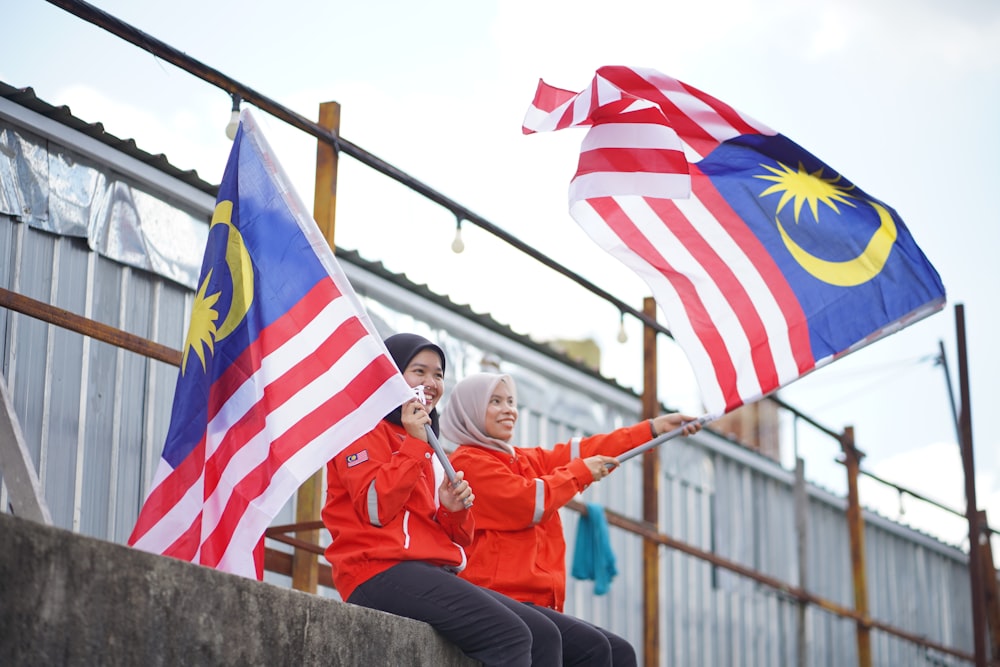 Zwei Frauen, die malaysische und malaysische Flaggen halten