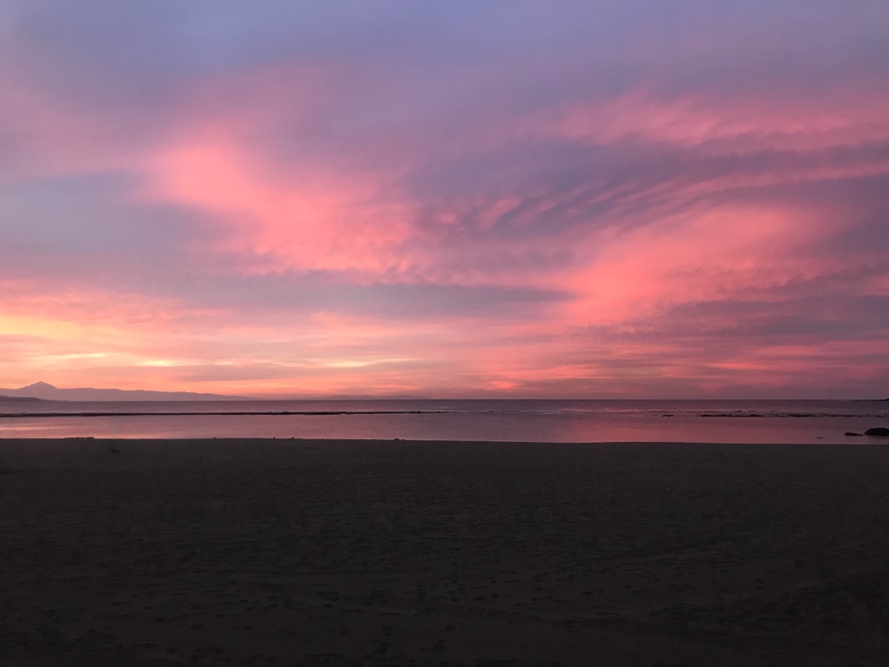 a pink and purple sunset over a beach