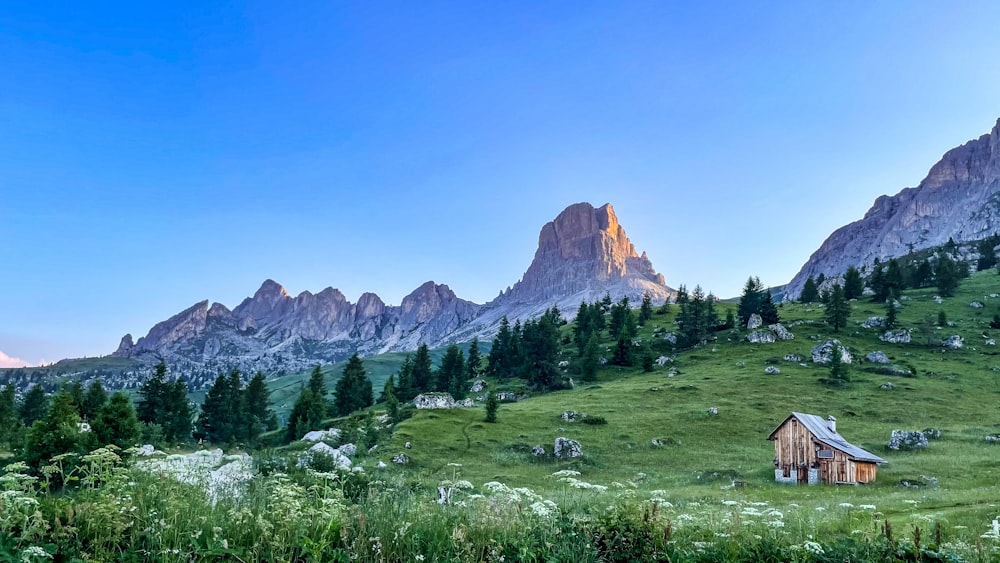 une maison sur une colline herbeuse avec des montagnes en arrière-plan