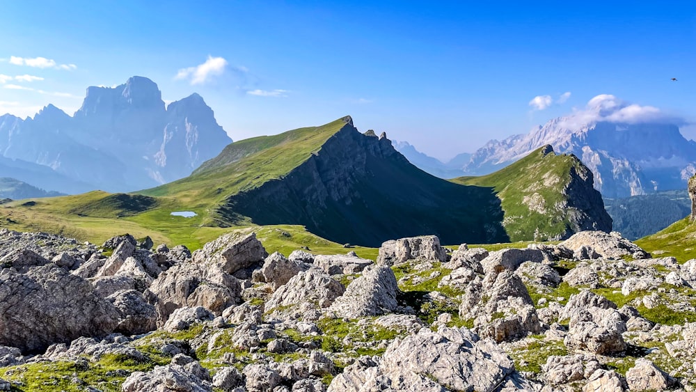 a mountain range with rocks and grass in the foreground