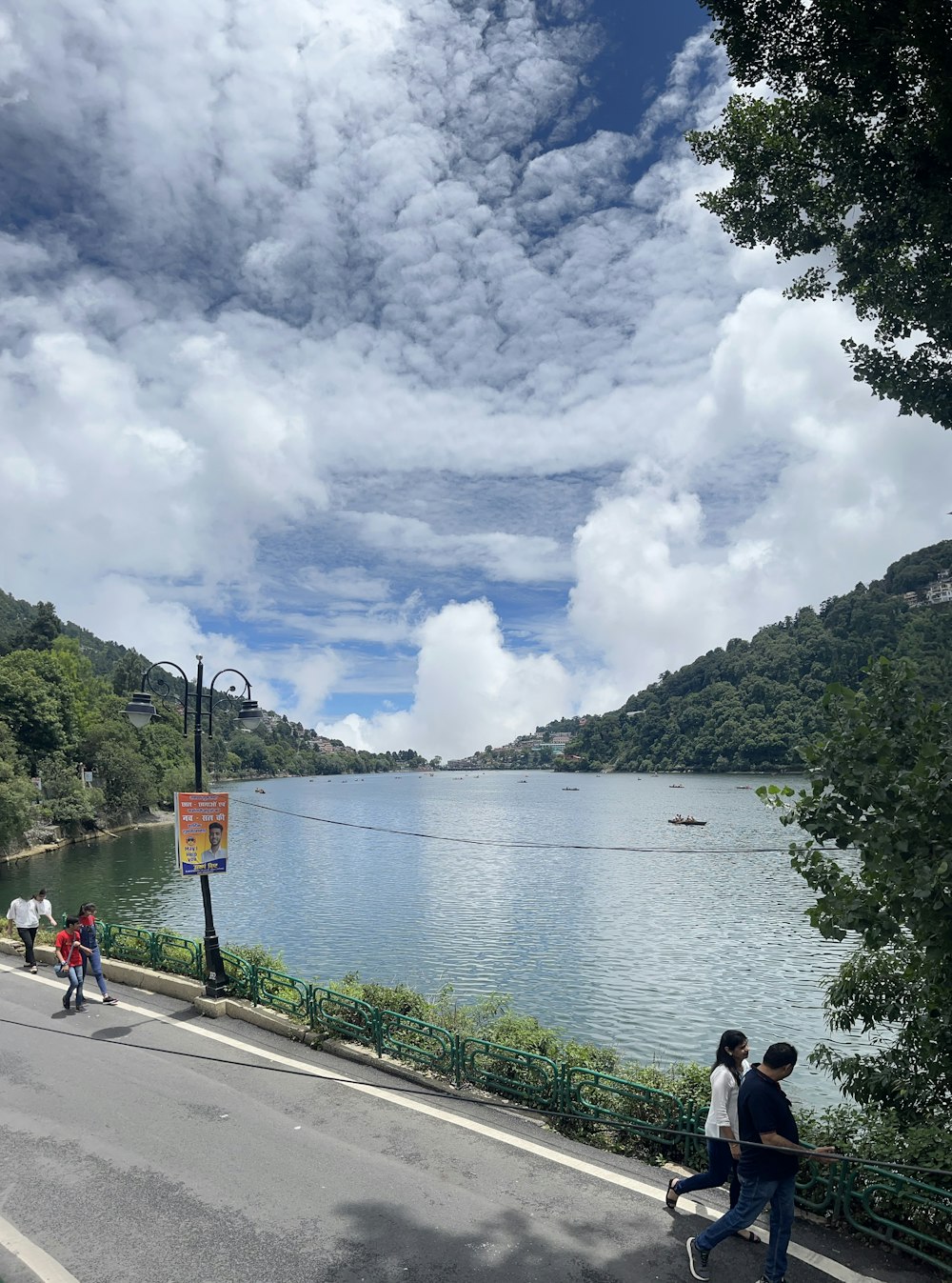 a group of people walking down a street next to a lake