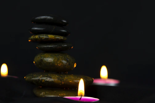 A peaceful corner with chakra stones aligned on a wooden tray beside a softly flickering candle.