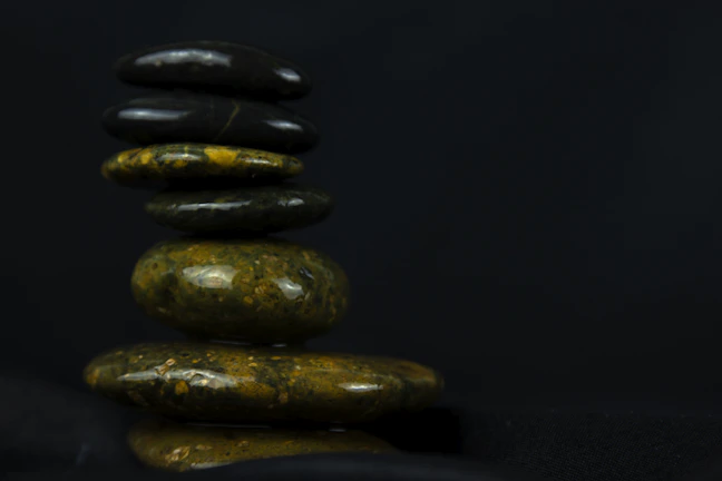 Soft green and white stones arranged thoughtfully on a wooden table symbolizing balance and intuition.