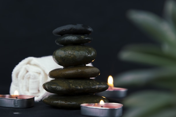 Close-up of smooth stones stacked neatly beside a small bowl of lavender oil.