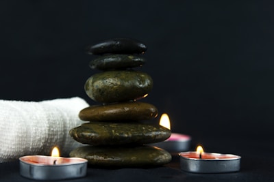 Close-up of aromatic candles and smooth stones arranged on a minimalist wooden tray.