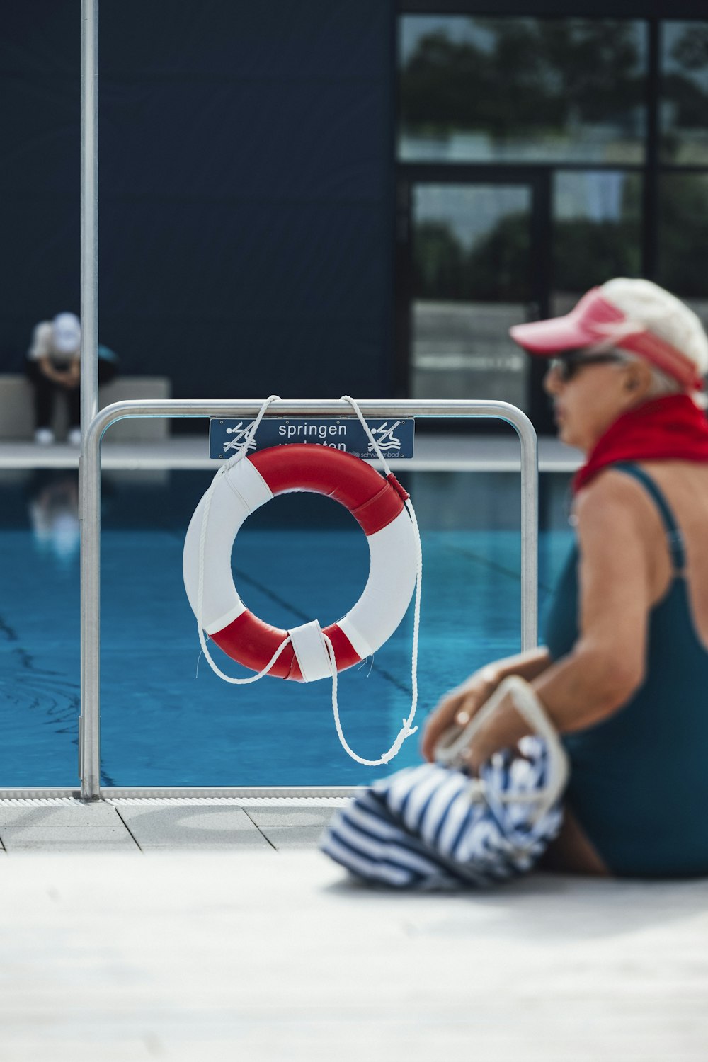 a woman sitting on the ground next to a swimming pool