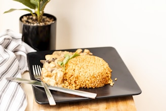 a black plate topped with food next to a potted plant