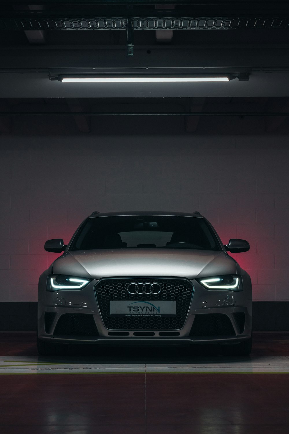 the front of a silver car in a parking garage