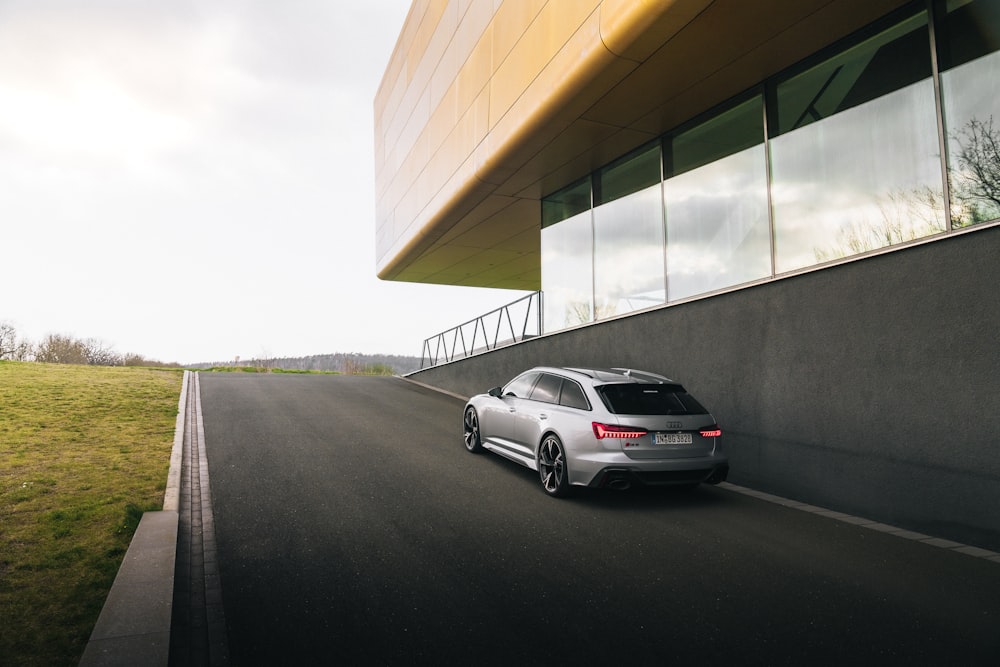 a silver car driving down a road next to a building