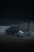 A sleek black sports car with a mirror-like shine under bright garage lights.