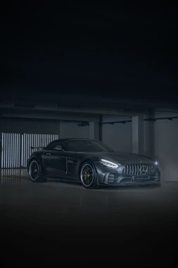 Sleek black sports car with a mirror-like shine under garage lights
