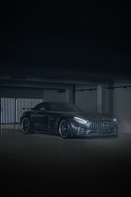 A sleek black sports car with a mirror-like shine under bright garage lights.