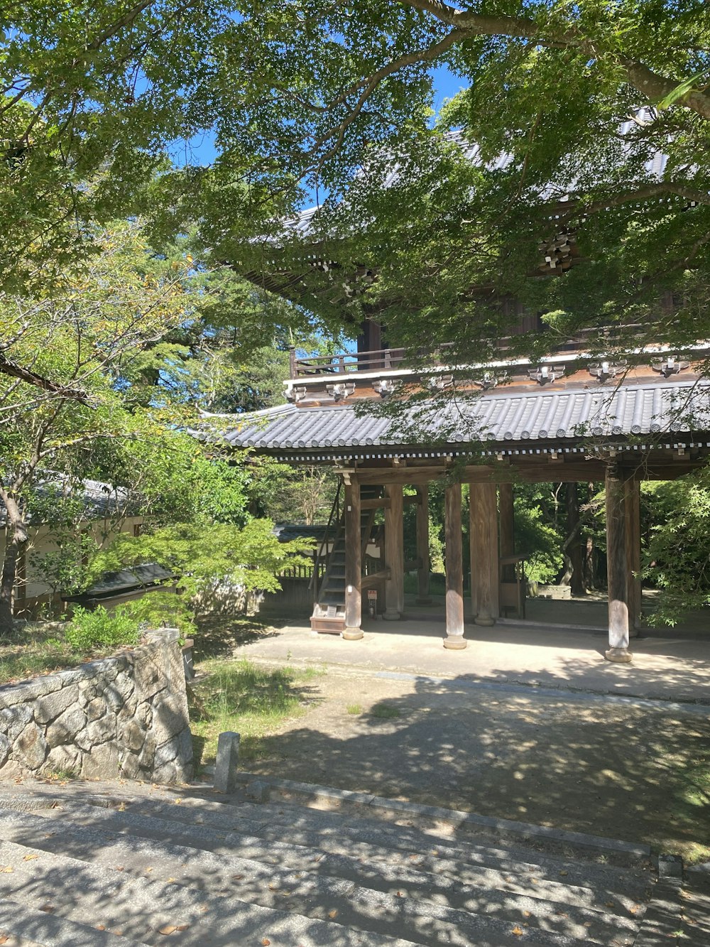 a stone walkway leading to a pavilion surrounded by trees