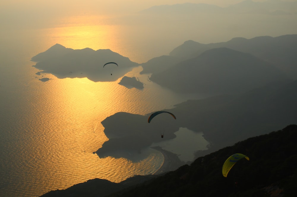 a couple of paraglides flying over a body of water