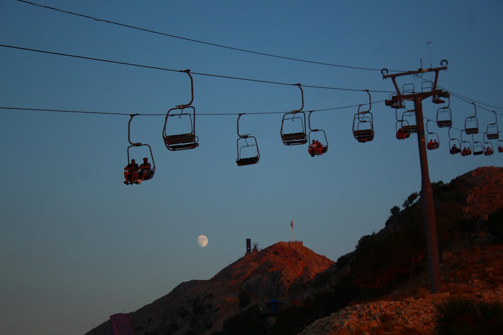a full moon is seen behind a line of gondolas