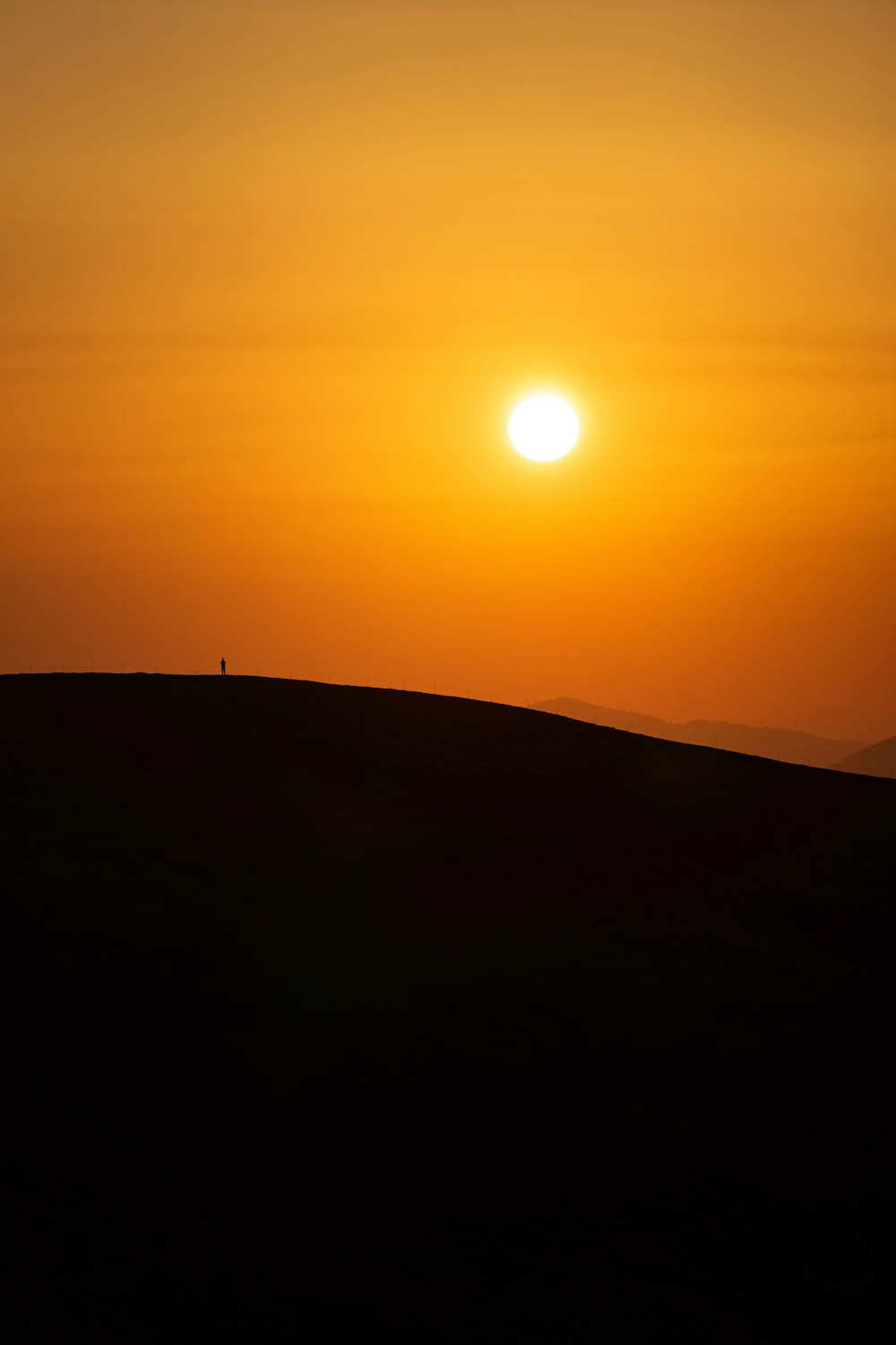 the sun is setting in the sky over a hill