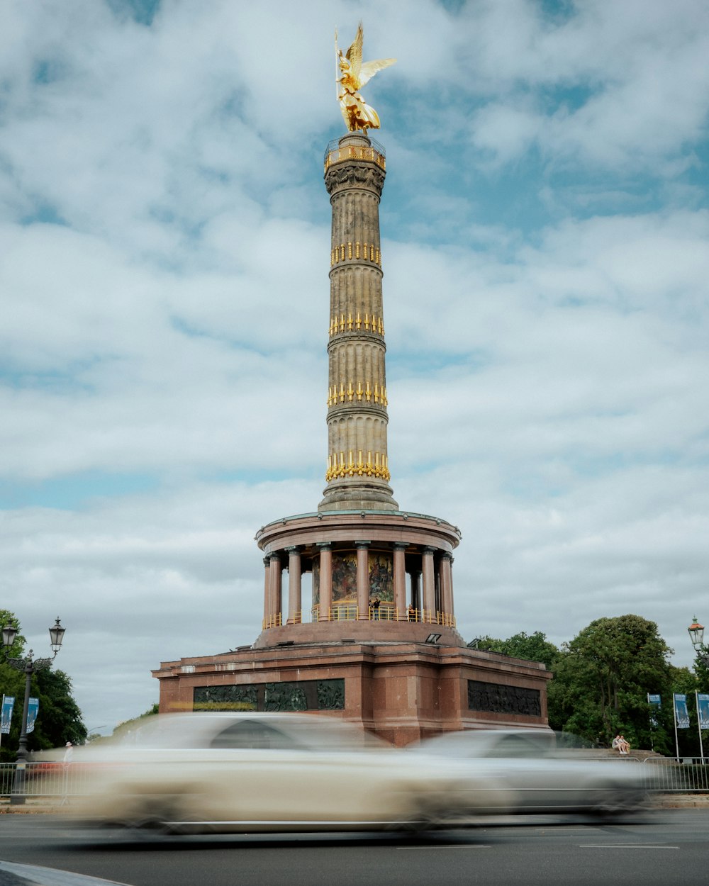 a car driving past a monument with a golden statue on top