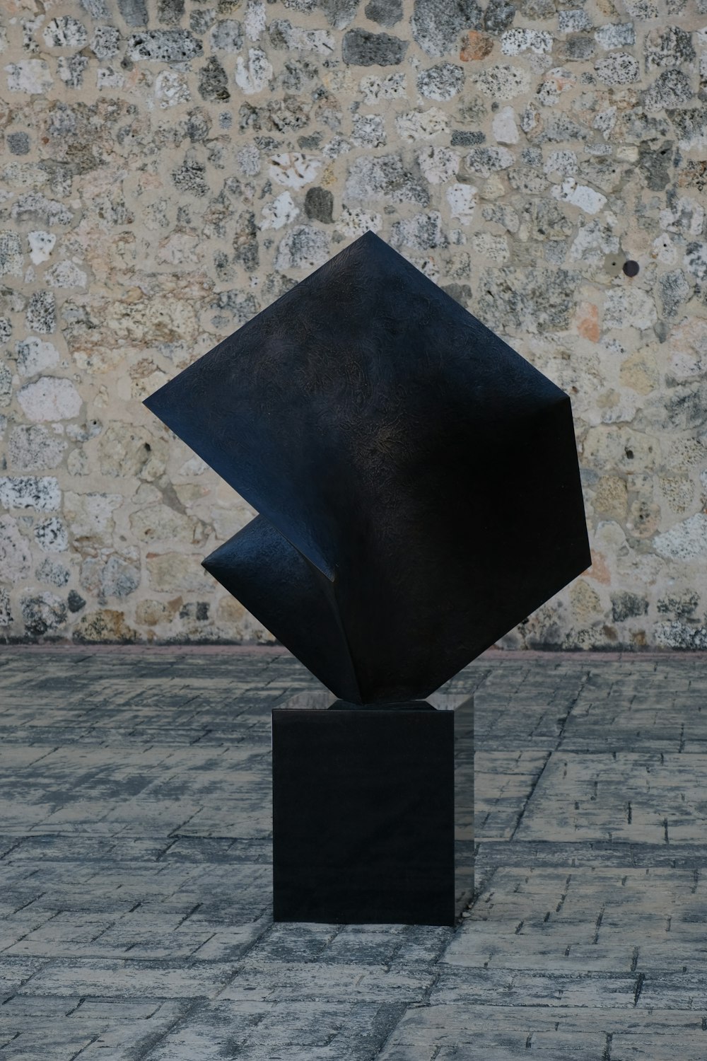 eine schwarze Skulptur, die auf einem Ziegelboden sitzt