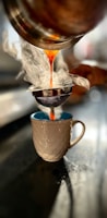 a person pouring liquid into a cup on a table