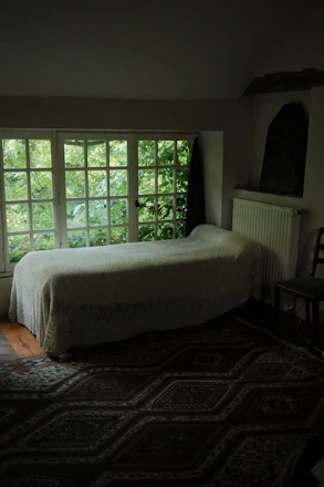 Cozy sunlit dorm room with comfortable beds overlooking a peaceful garden.