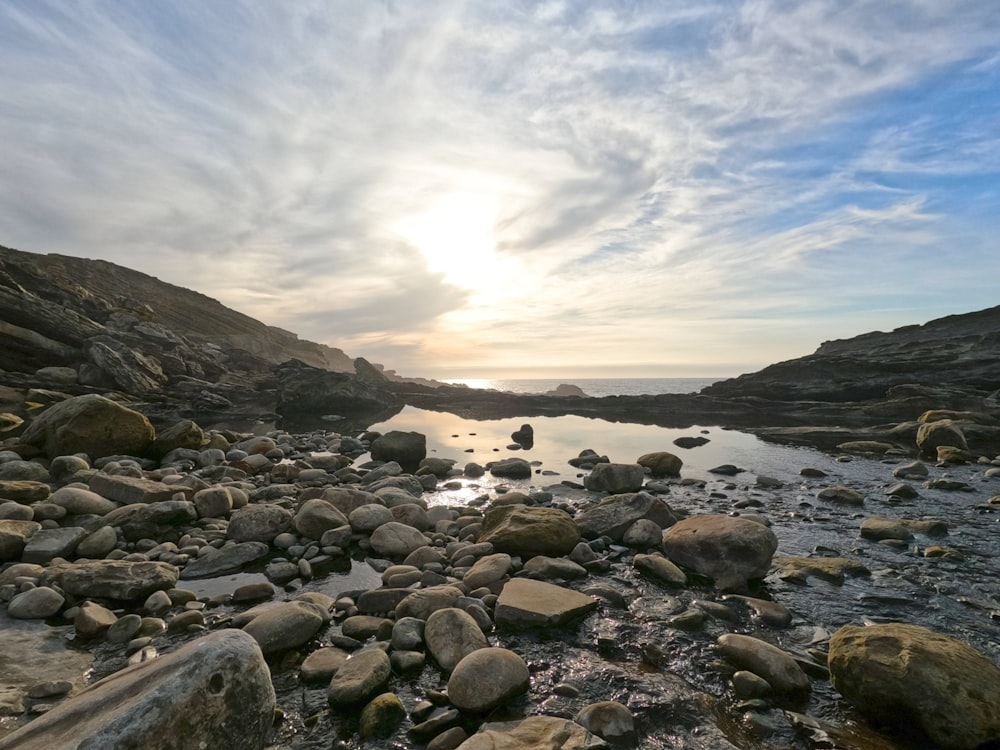 El sol se está poniendo sobre una playa rocosa