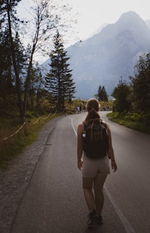 a woman with a backpack walking down a road